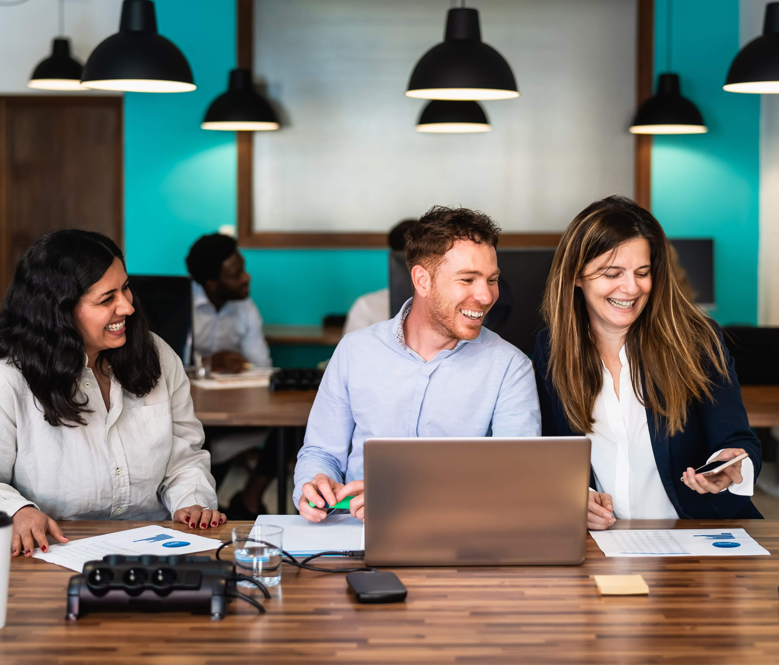 business-team-3 three people sitting together at their desk smiling