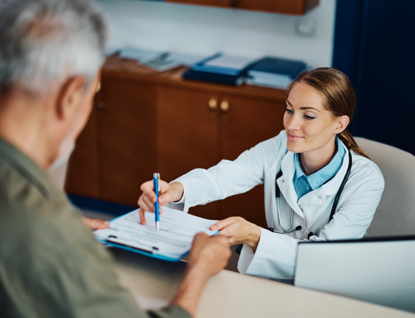 happy-doctor-helping-her-mature-patient-to-fill-ou-2023-02-07-22-56-04-utc-cropped